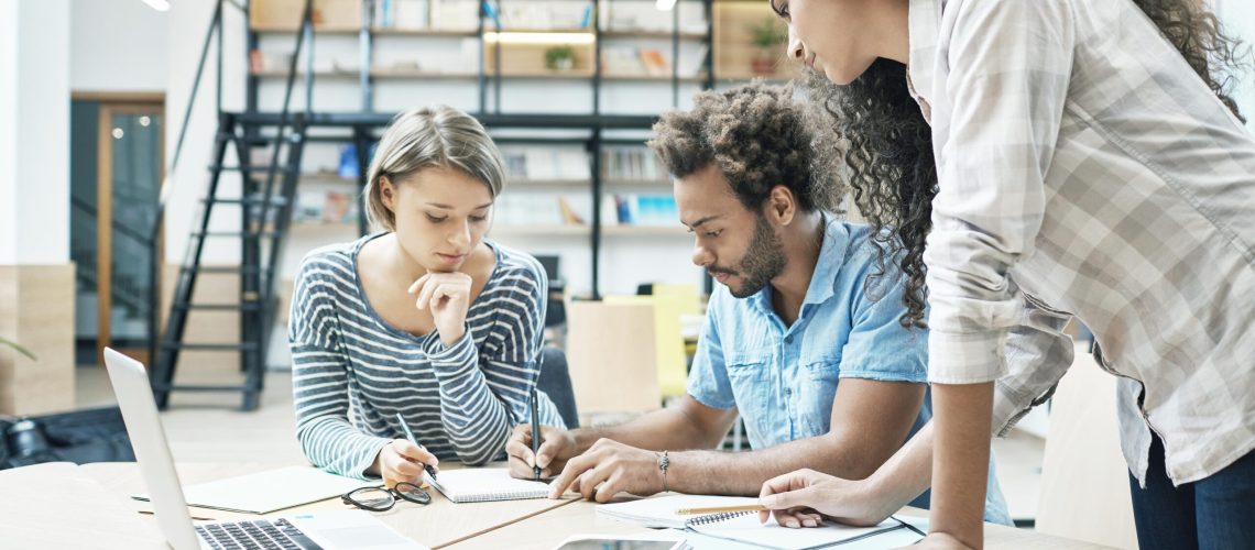 group-of-three-young-multi-ethnic-successful-business-people-sitting-in-coworking-space-talking-about-new-project-of-competitor-team-making-plans-to-bypass-their-project - klein