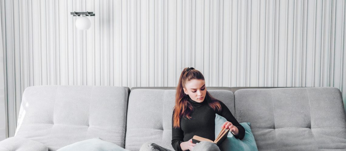 young-attractive-girl-couch-reads-paper-book-mental-development-useful-use-time-home-home-comfort